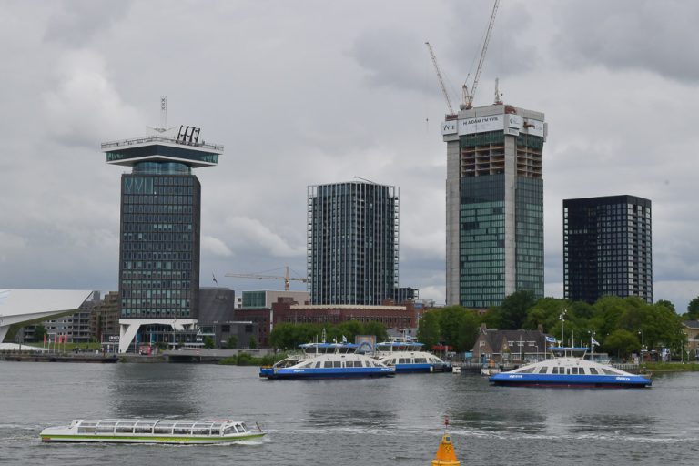 Die Türme des A'DAM Tower und der Nachbargebäude am Nordufer des IJ mit Fähren im Vordergrund