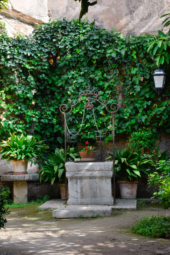 Garten mit Efeu und Brunnen im Hochformat