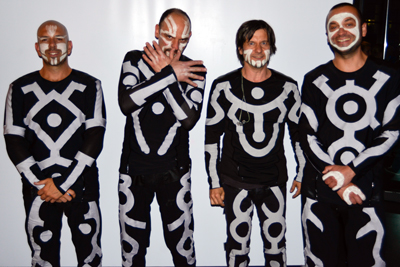 Vier Mitglieder der Blue Man Group in schwarz-weißen Anzügen