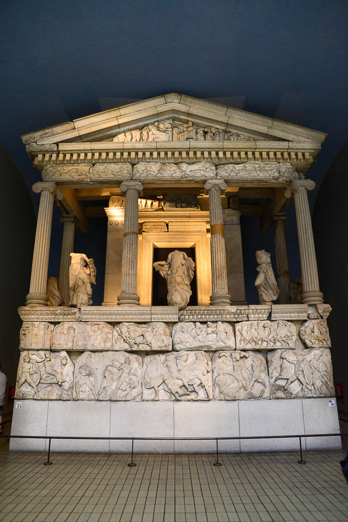 Antikes Bauwerk aus Marmor mit Reliefs in einem dunklen Saal