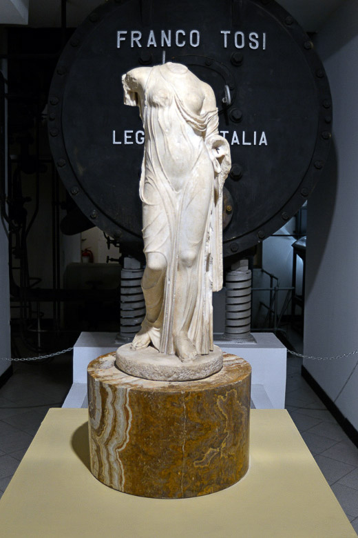Statue vor einem Kessel mit Aufschrift im Hochformat