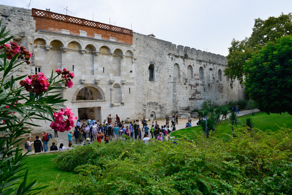 Mauer des Diokletianpalastes mit Besuchern und Blumen im Vordergrund