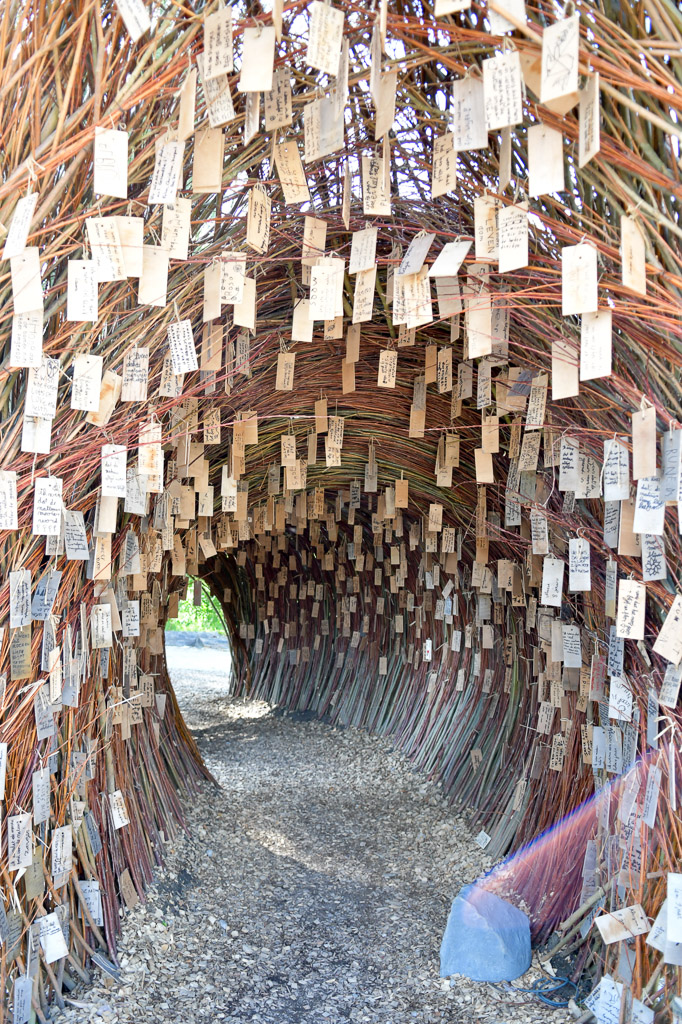 Tunnel aus Ästen mit hängenden Holzschildern