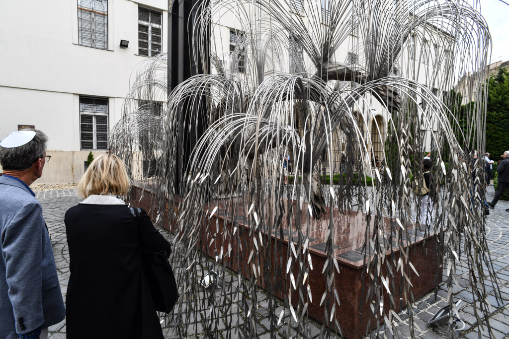 Besucher vor dem Mahnmal aus Metall mit Namensblättern