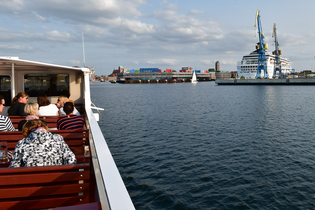 Fahrgäste an Deck mit Werft im Hintergrund
