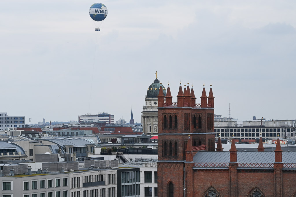 Blick über Dächer mit Backsteinkirche und Ballon