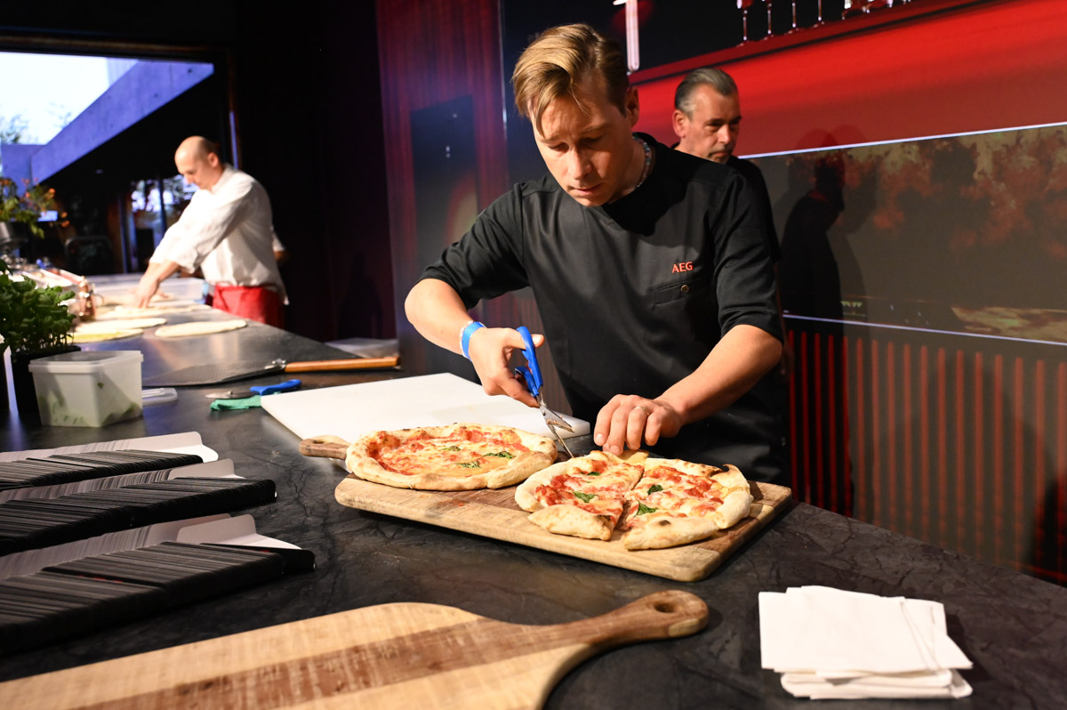 Koch belegt Pizza auf der Bühne