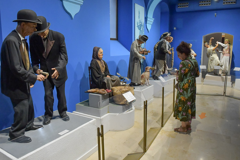Figurengruppe mit Menschen in Alltagskleidung vor einer blauen Wand