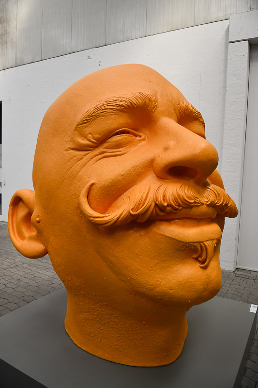 Orangefarbene Skulptur eines Kopfes im Hochformat