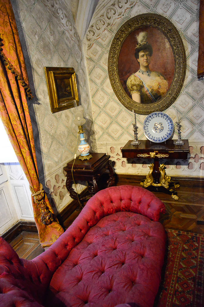 Salon mit Porträts und rotem Sofa