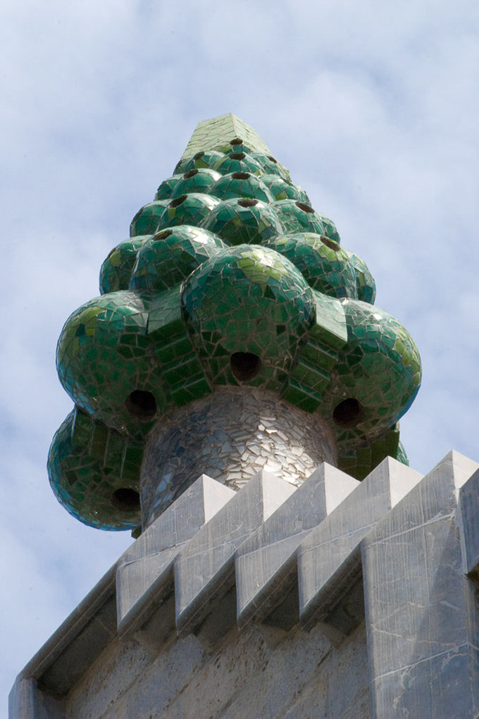 Grüner Kaminaufsatz mit Mosaik vor blauem Himmel im Hochformat