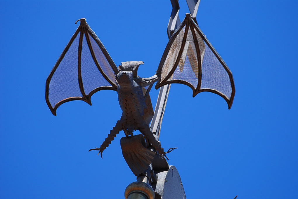 Metallfigur eines Drachen mit Flügeln vor blauem Himmel