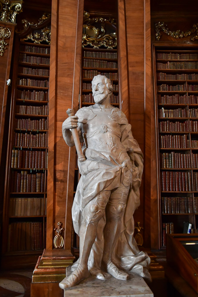 Marmorstatue vor Bücherregalen im Hochformat