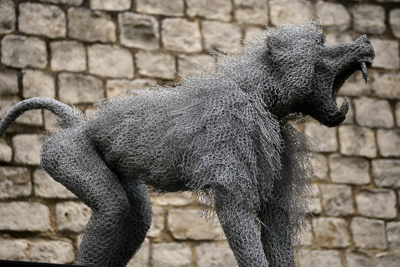Metallskulptur eines brüllenden Tieres an einer Steinmauer