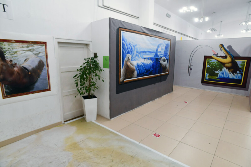Ausstellungsraum mit 3D-Gemälden und einer Zimmerpflanze