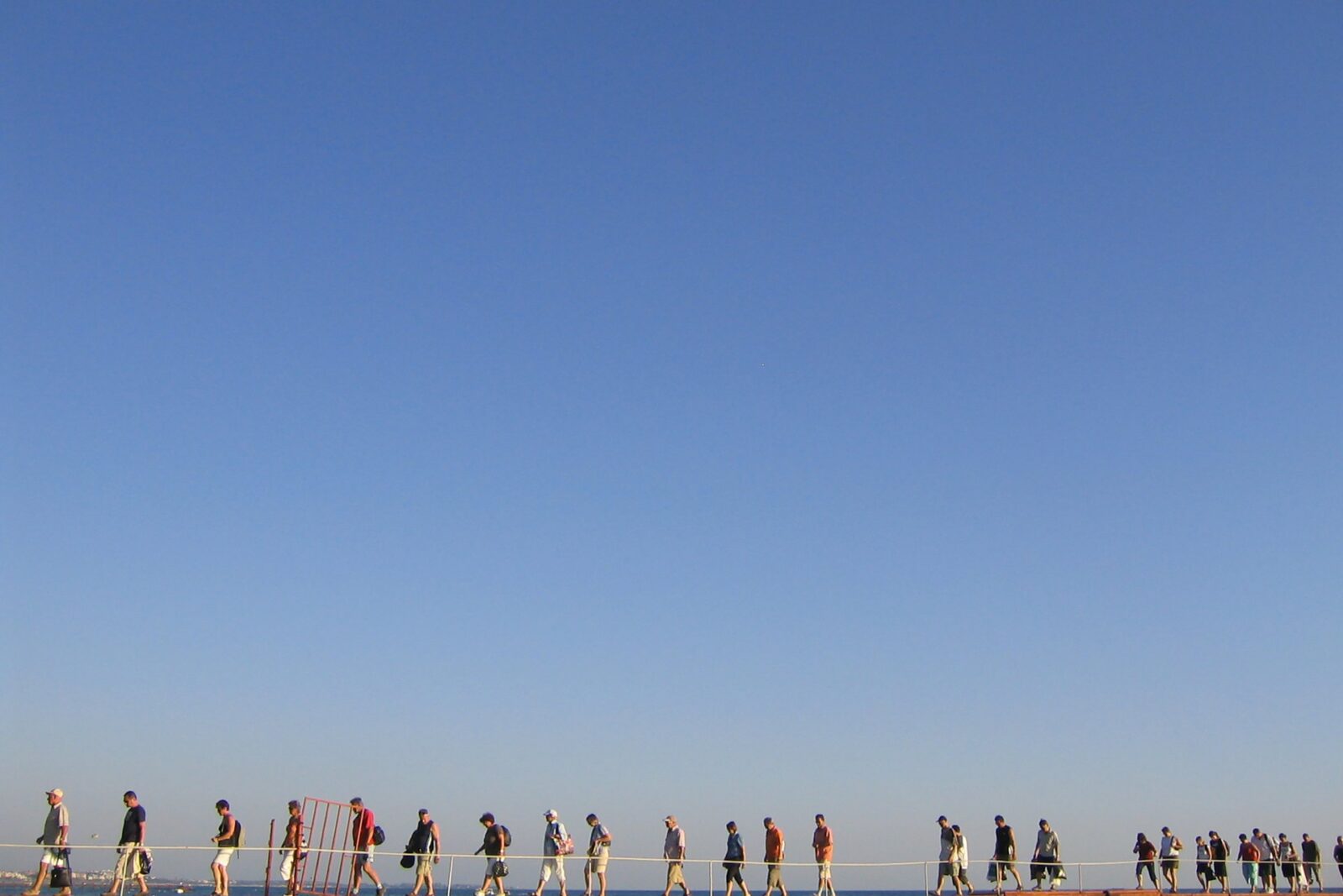 Menschen auf einem Küstenweg vor blauem Himmel