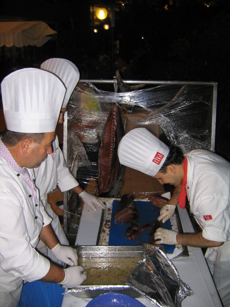 Köche bereiten am Buffet ein Gericht zu im Hochformat