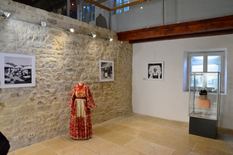 Ausstellungsraum mit einem roten Trachtenkleid und historischen Fotografien
