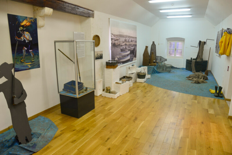 Ausstellungsraum mit Alltagsgegenständen und Fotografien