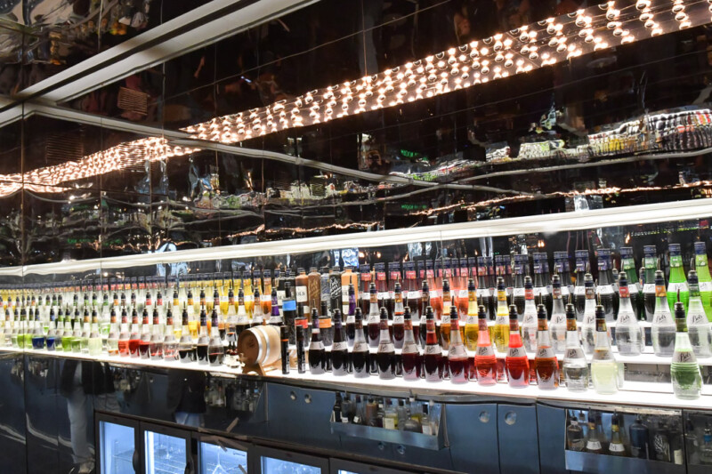 Bar mit beleuchteten Regalen voller Likörflaschen im House of Bols