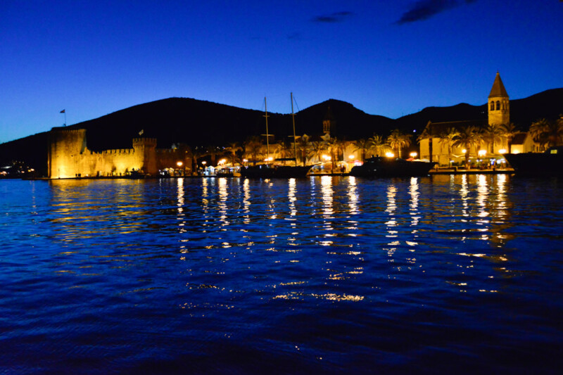 Die beleuchtete Altstadt von Trogir am Abend vom Wasser aus