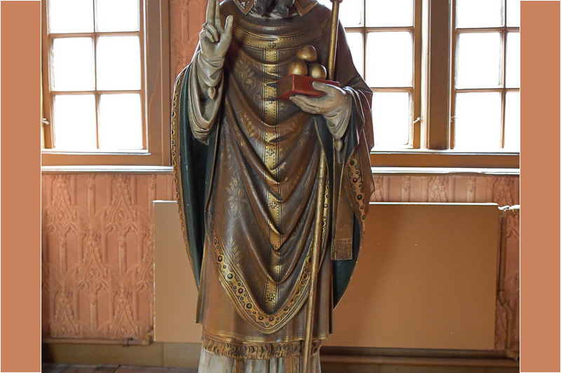 Holzfigur eines Heiligen am Fenster