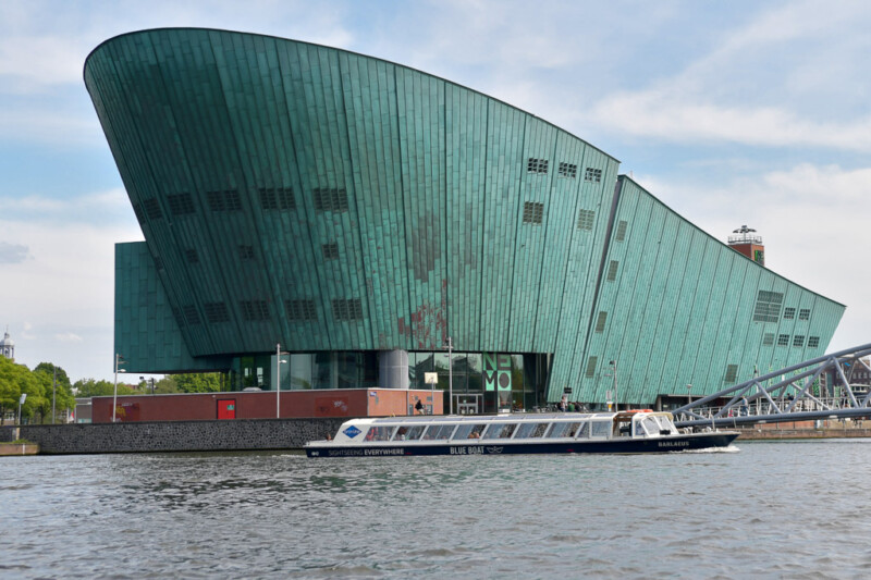 Das NEMO-Gebäude vom Wasser aus mit einem Ausflugsboot