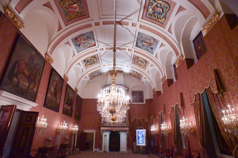 Gewölbter Saal mit Deckengemälden und Kronleuchter