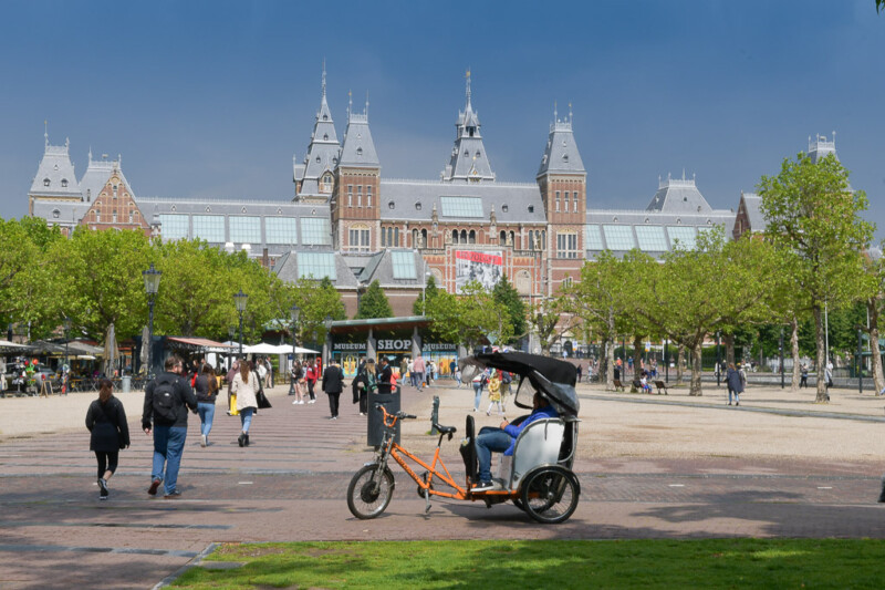 Das Rijksmuseum vom Museumplein aus gesehen, davor eine Fahrradrikscha