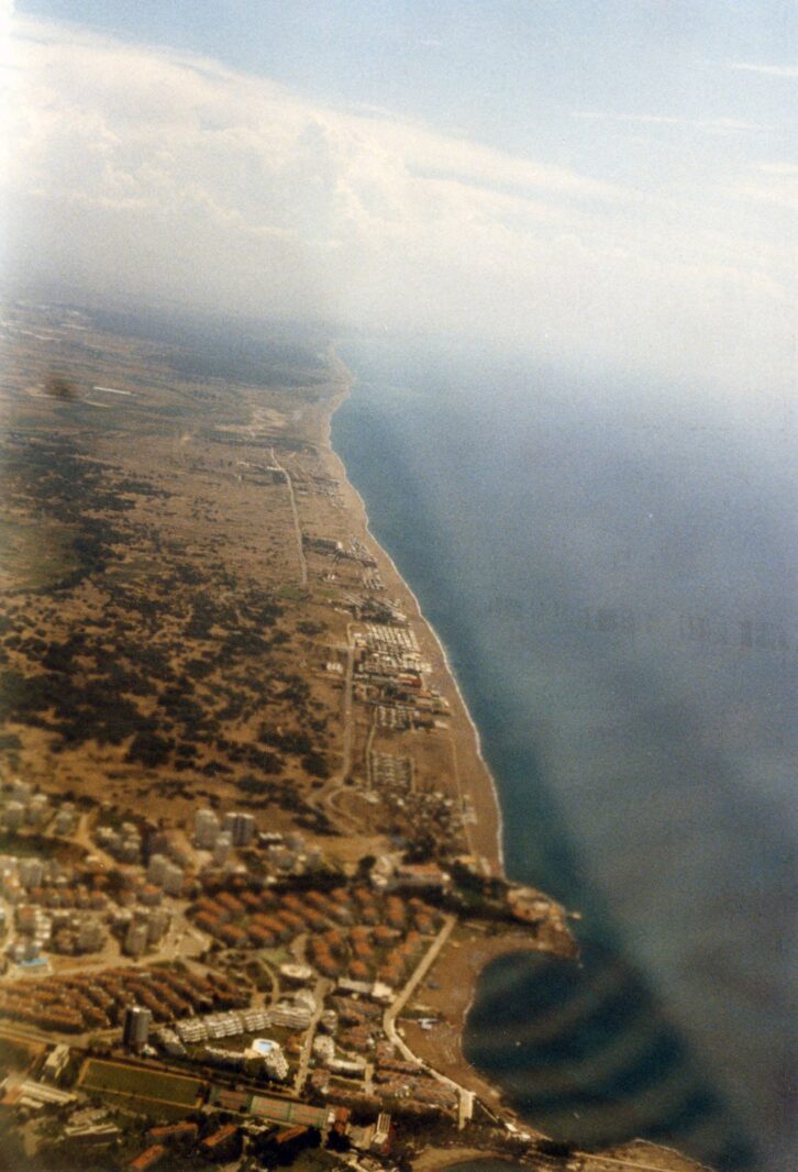 Küste mit langem Sandstrand aus dem Flugzeug im Hochformat