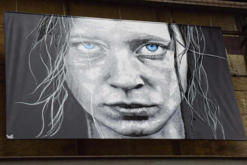 Schwarz-weißes Gesicht mit blauen Augen als großes Wandbild