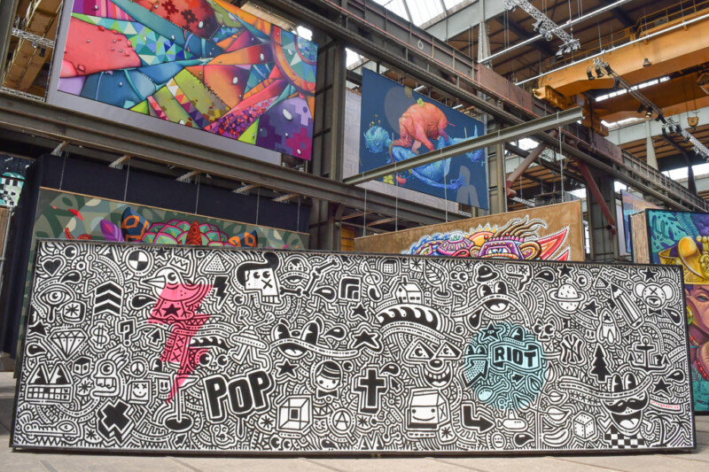 Schwarz-weißes Wandbild mit Comicmotiven vor farbigen Werken